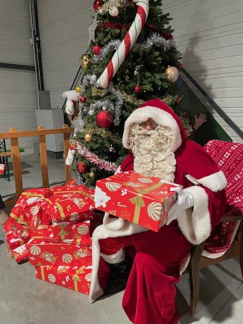 Père Noël qui remet un cadeau lors d'un arbre de noël d'entreprise