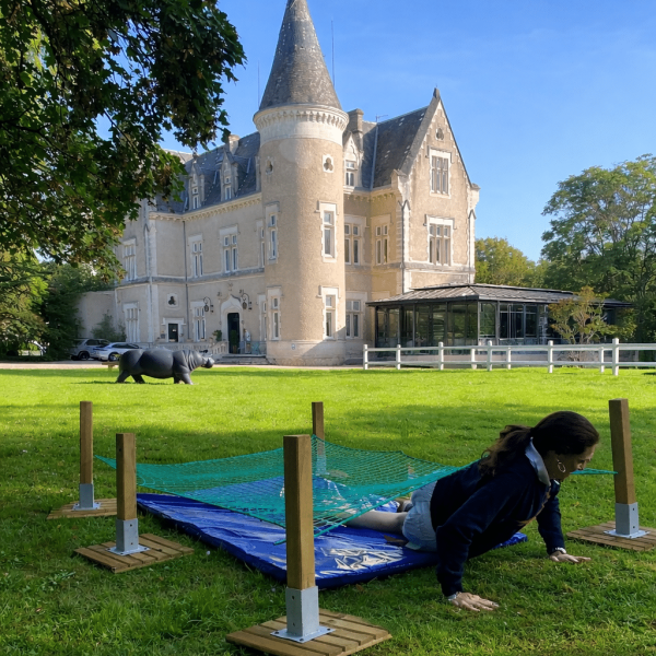 Jeune femme qui rampe sous un filet lors d'une animation team building en Dordogne